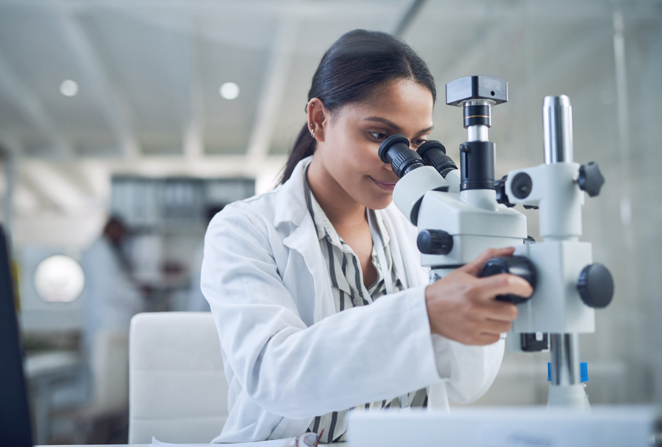 Science, microscope and innovation with a woman in a laboratory for medical research or experiment. Healthcare, medicine and a young indian engineer working in a lab for pharmaceutical development